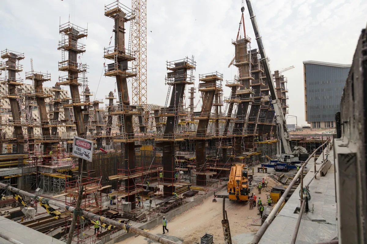 Chantier de construction avec structures en béton, échafaudages et grues en activité