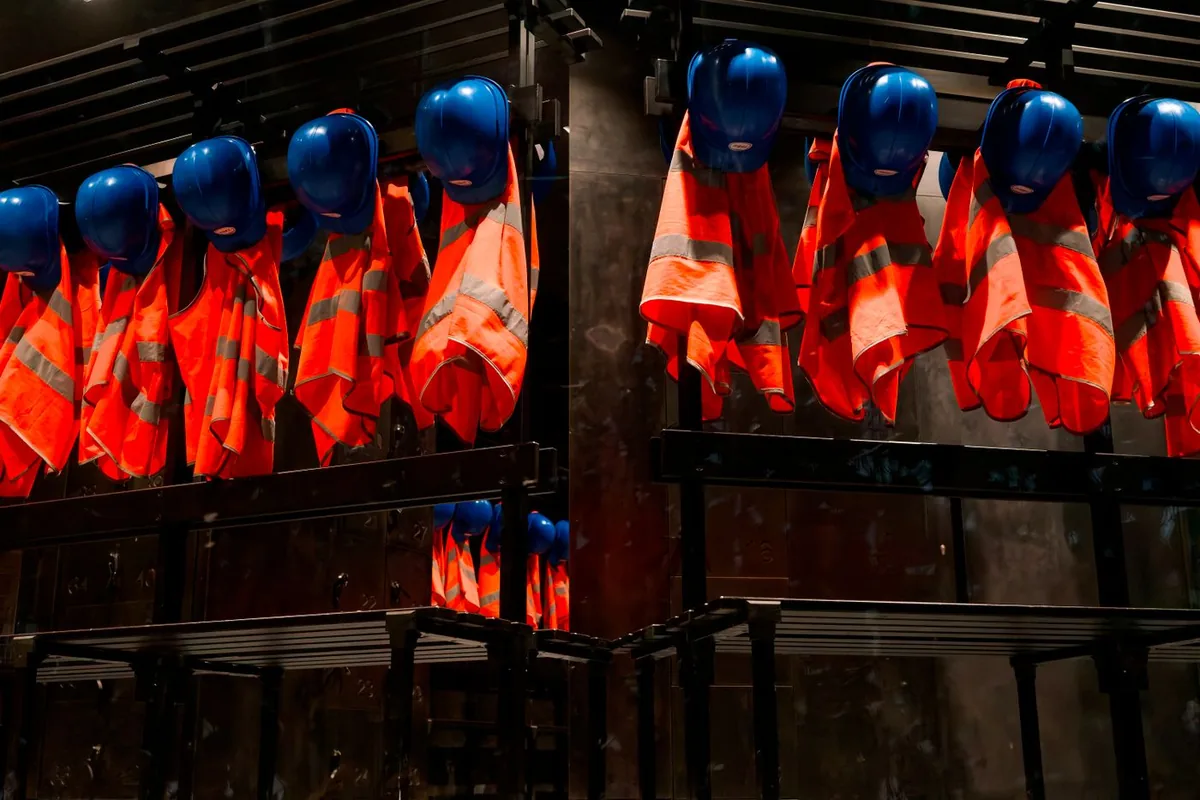 Gilets de haute visibilité orange et casques de chantier bleus suspendus à un portant