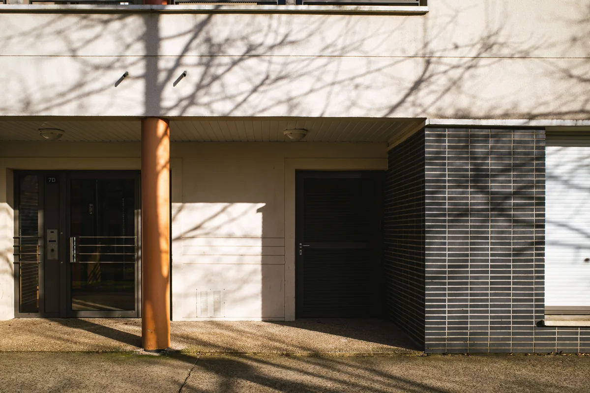 Entrée d'un immeuble résidentiel contemporain avec accès couvert et parement sombre